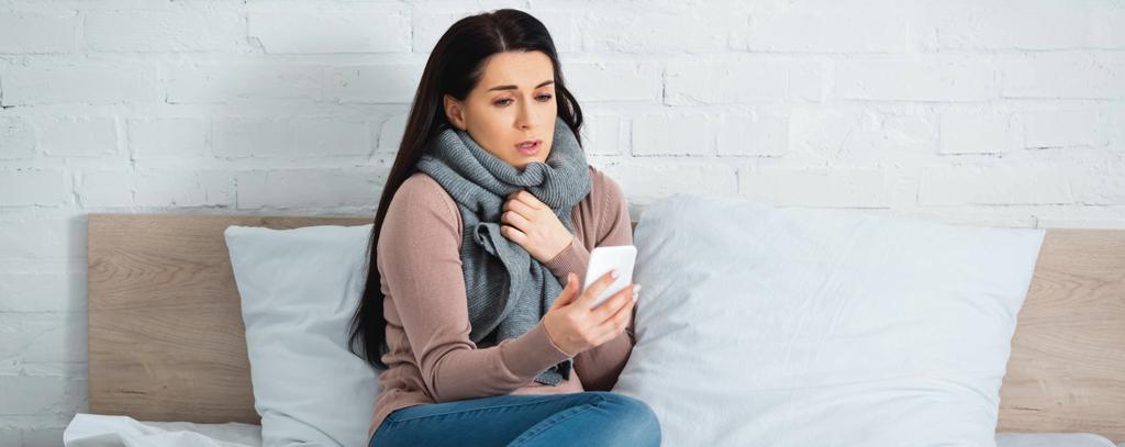 Panoramabild einer attraktiven, grippekranken Frau mit Online-Arztkonsultation auf dem Smartphone - Foto, Bild