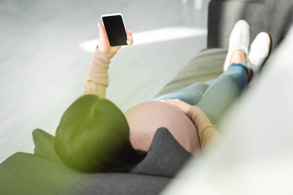 geschnittene Ansicht einer schwangeren Patientin mit Online-Konsultation mit dem Arzt auf dem Smartphone - Foto, Bild