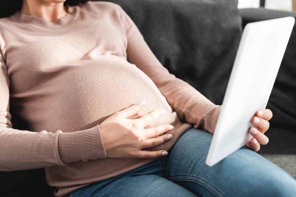 обрезанный взгляд беременной женщины, имеющей онлайн консультации с врачом на цифровые таблетки на дому
 - Фото, изображение