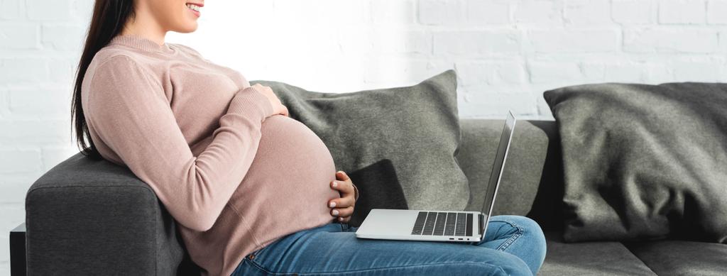 panoramiczne ujęcie uśmiechniętej kobiety w ciąży po konsultacji online z lekarzem na laptopie w domu - Zdjęcie, obraz
