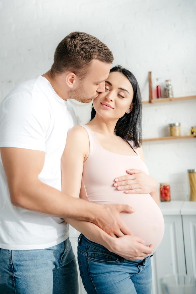 mari tendre toucher le ventre de la femme enceinte et l'embrasser dans la cuisine
 - Photo, image