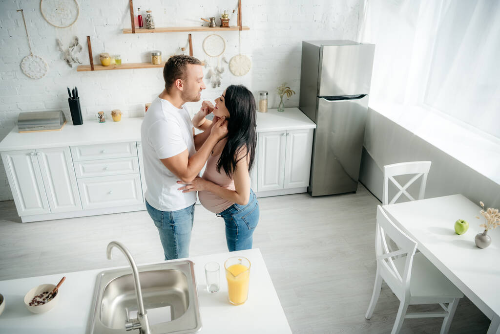 familia embarazada feliz abrazo en la cocina con jugo de naranja
 - Foto, imagen