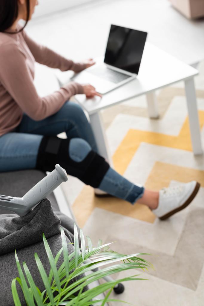 enfoque selectivo de la mujer con la pierna rota que tiene consulta en línea con el médico en el ordenador portátil en casa
 - Foto, imagen