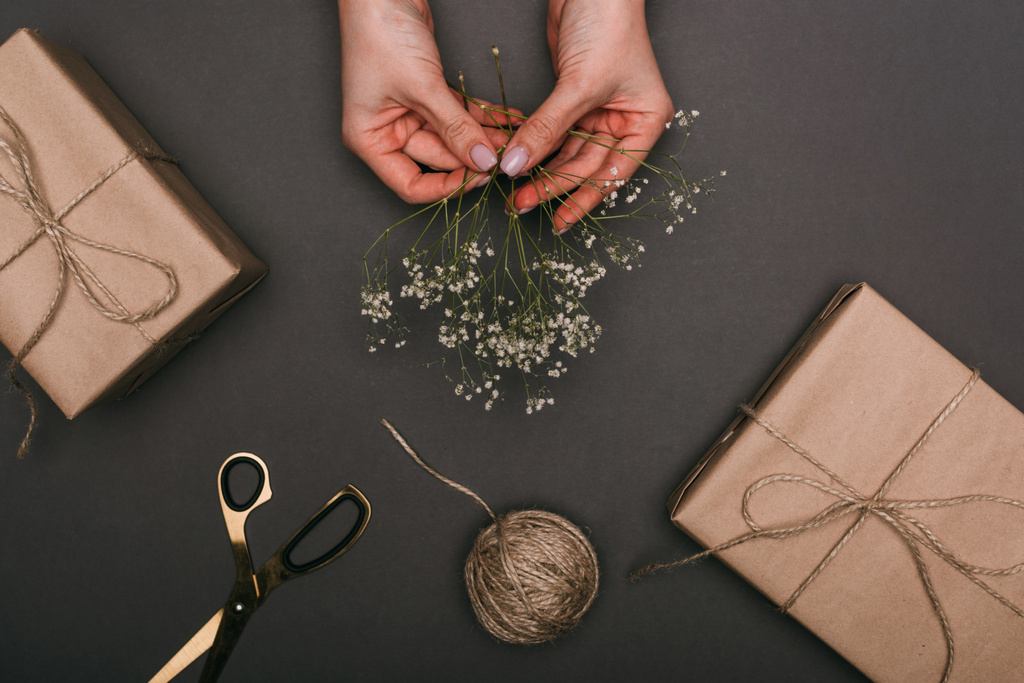 Kırpılmış kadın hediye kutularını el işi kağıt, sicim ve çiçeklerle dolduruyor. - Fotoğraf, Görsel