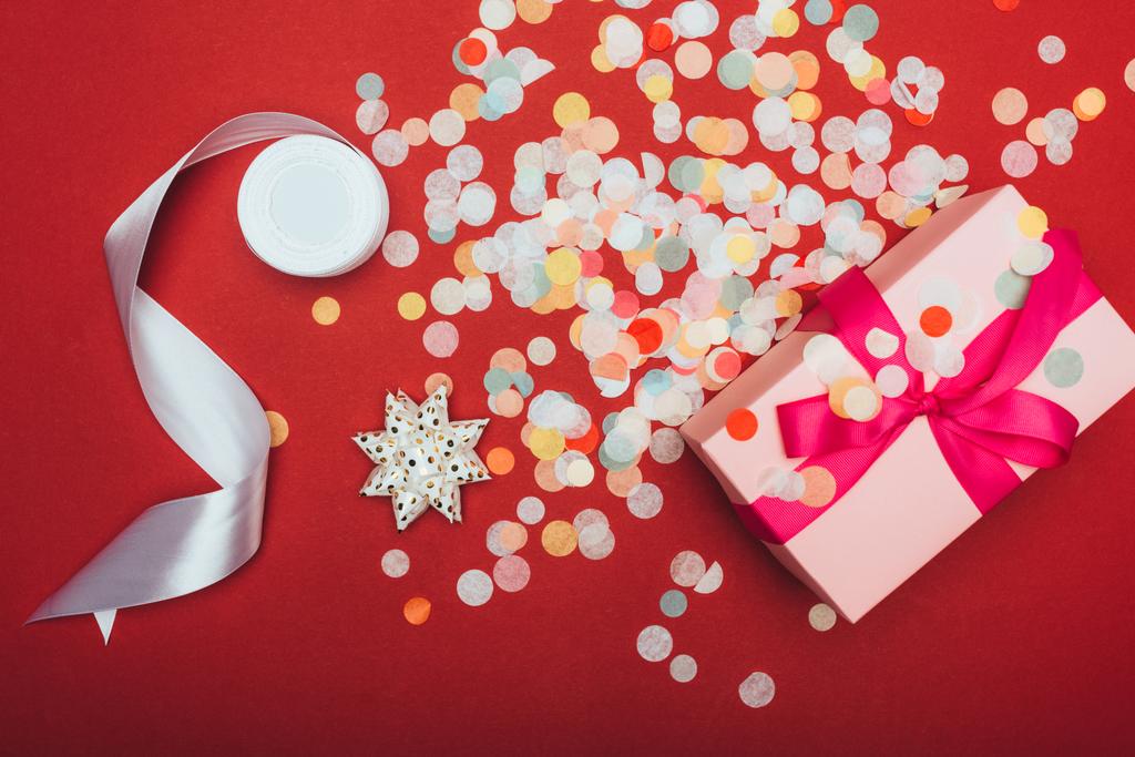 вид зверху на одне Різдво з бантом, стрічкою та конфетті на червоному
 - Фото, зображення
