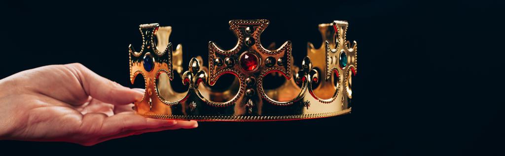 cropped view of woman holding golden crown with gemstones, isolated on black, panoramic shot - Photo, Image