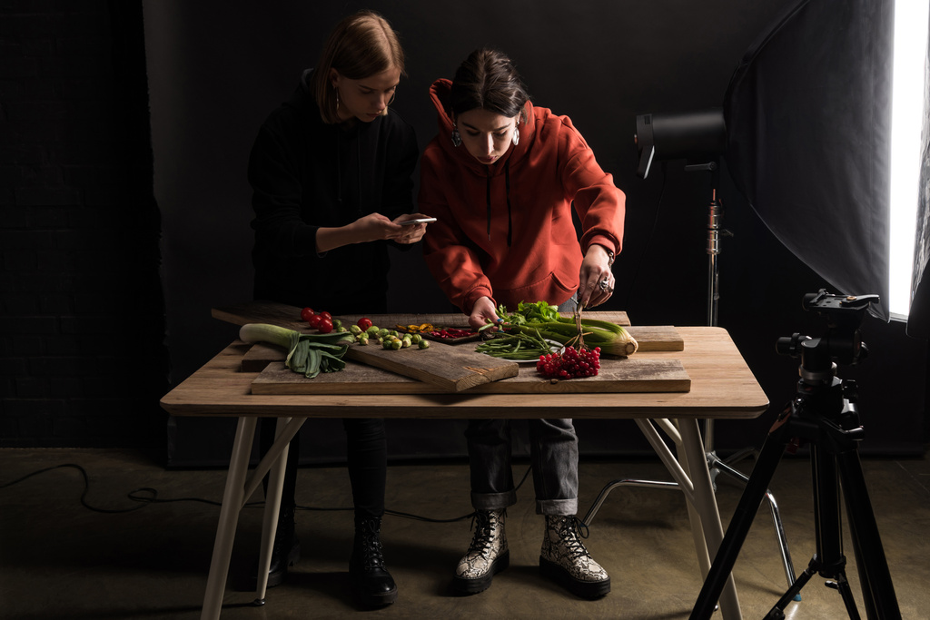 zwei Fotografen, die Nahrungsmittelkompositionen für kommerzielle Fotografien mit dem Smartphone machen - Foto, Bild