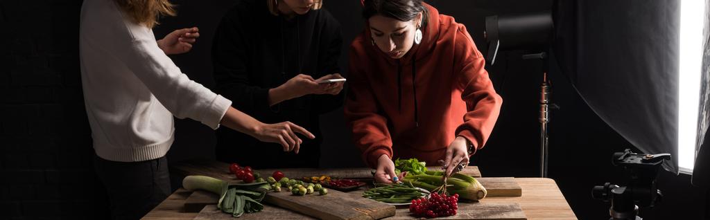 vista recortada de fotógrafos haciendo la composición de alimentos para la fotografía comercial en el teléfono inteligente, plano panorámico
 - Foto, imagen