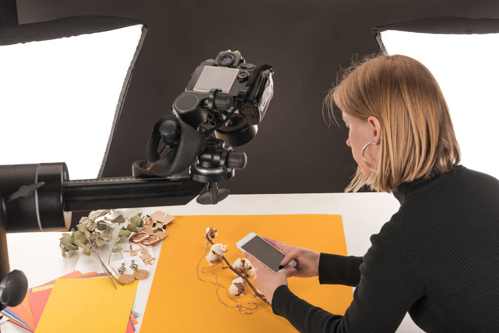 fotograf robi zdjęcie kompozycji z kwiatem bawełny i akcesoriami na smartfonie - Zdjęcie, obraz