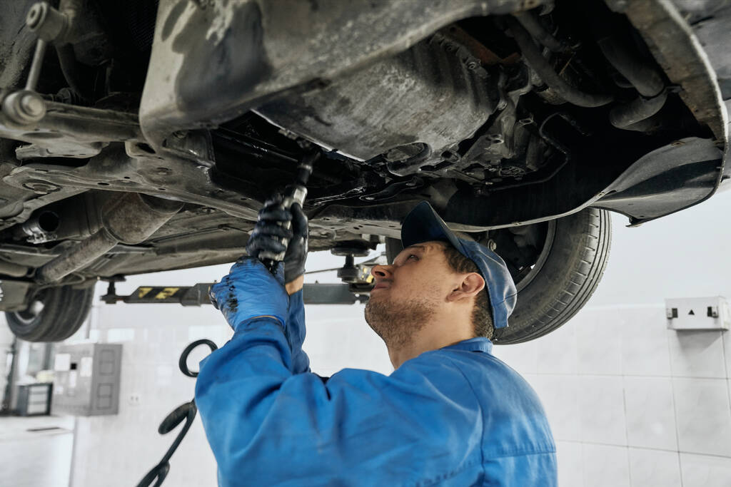 Mécanicien professionnel travaillant avec des outils sous voiture relevée
 - Photo, image