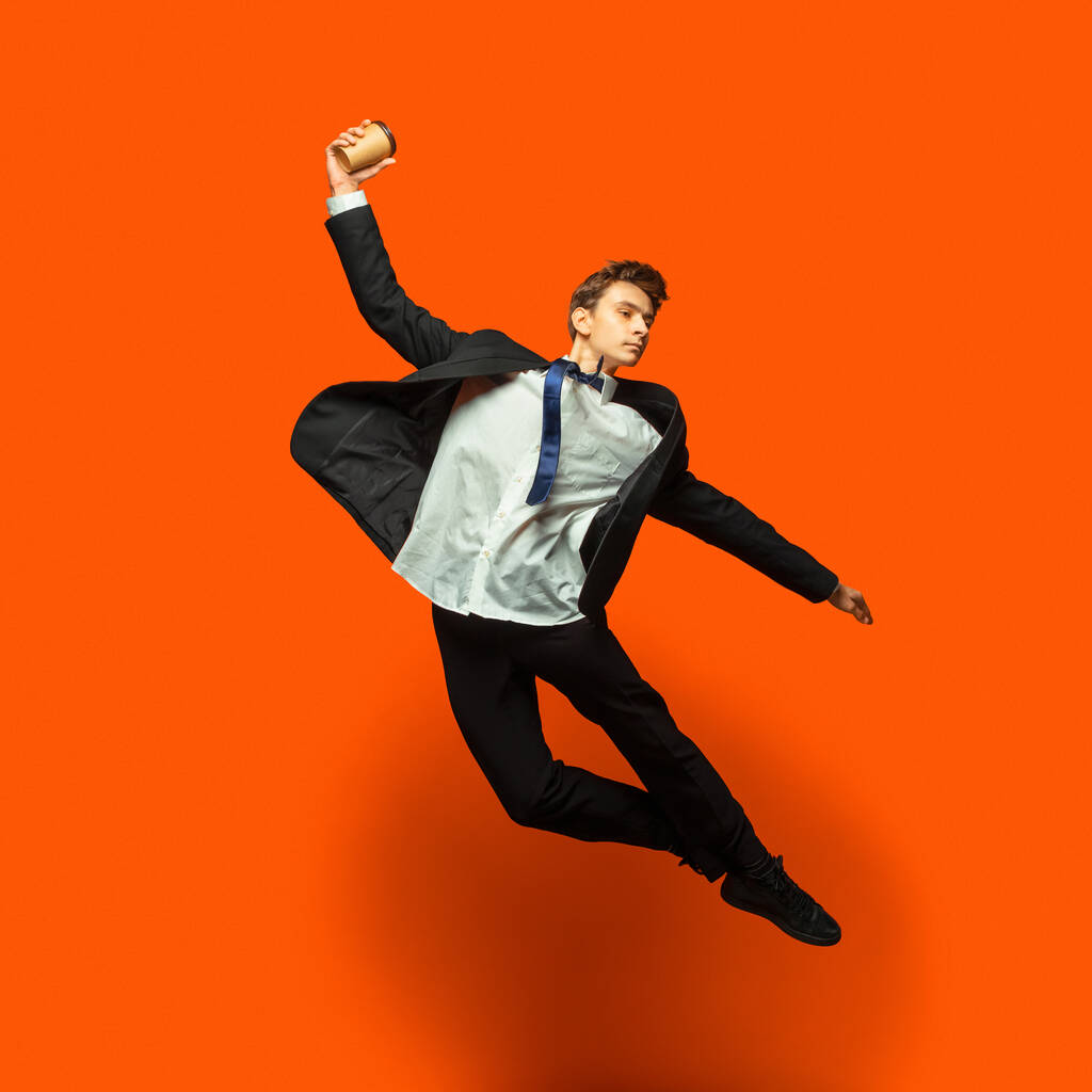 Мужчина в повседневной офисной одежде, прыгающий на фоне студии
 - Фото, изображение