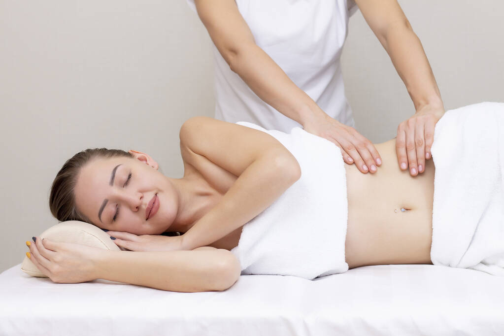 Terapeuta masujący kobiecy żołądek. Masaż i pielęgnacja ciała. Spa masaż ciała kobieta ręce leczenie.  - Zdjęcie, obraz