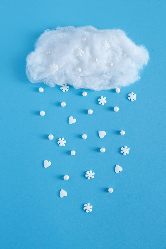 Schneefall aus einer Wolke aus Watte auf blauem Hintergrund - Foto, Bild