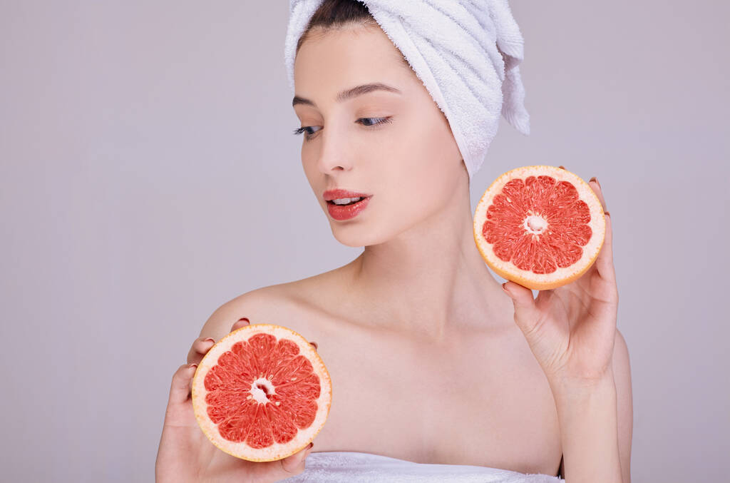 Young beauty is holding a juicy grapefruit in her hands. - Photo, Image