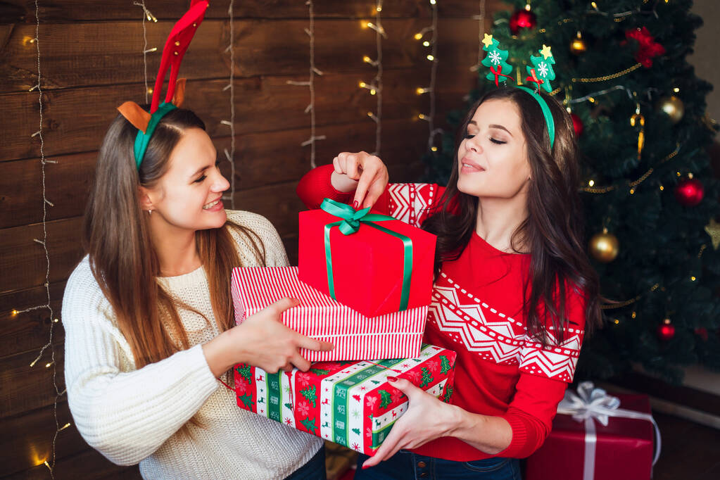 Dos novias riendo y compartiendo regalos de Navidad en casa
 - Foto, imagen