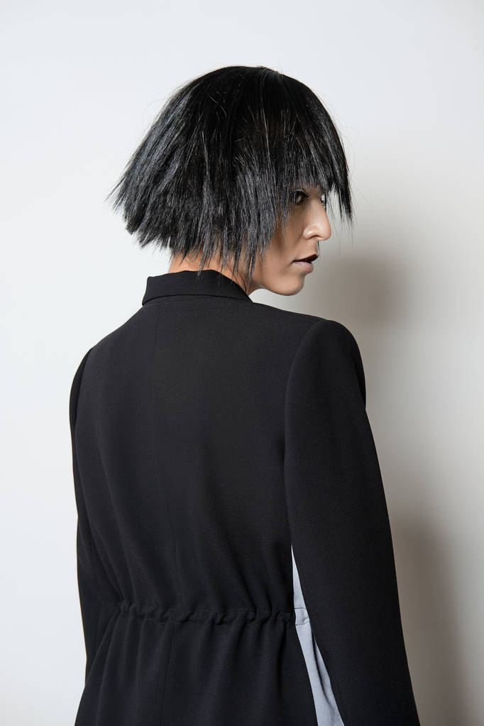 Модель моды в коротком черном парике позирует в профиль
 - Фото, изображение