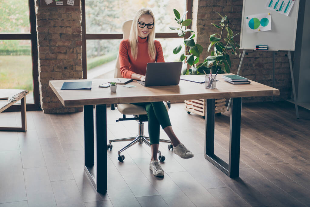 Pełne ciało zdjęcie udanej uroczej kobiety właściciel firmy siedzieć stół pracy laptop do startup projekt nosić czerwony golf w biurze loft pracy - Zdjęcie, obraz
