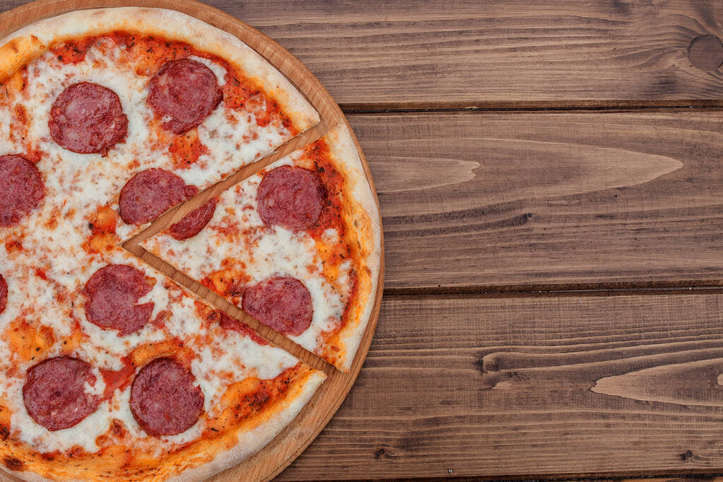Pizza piccante italiana con salame su sfondo in legno scuro vista dall'alto. Cucina tradizionale italiana. Street food popolare
 - Foto, immagini
