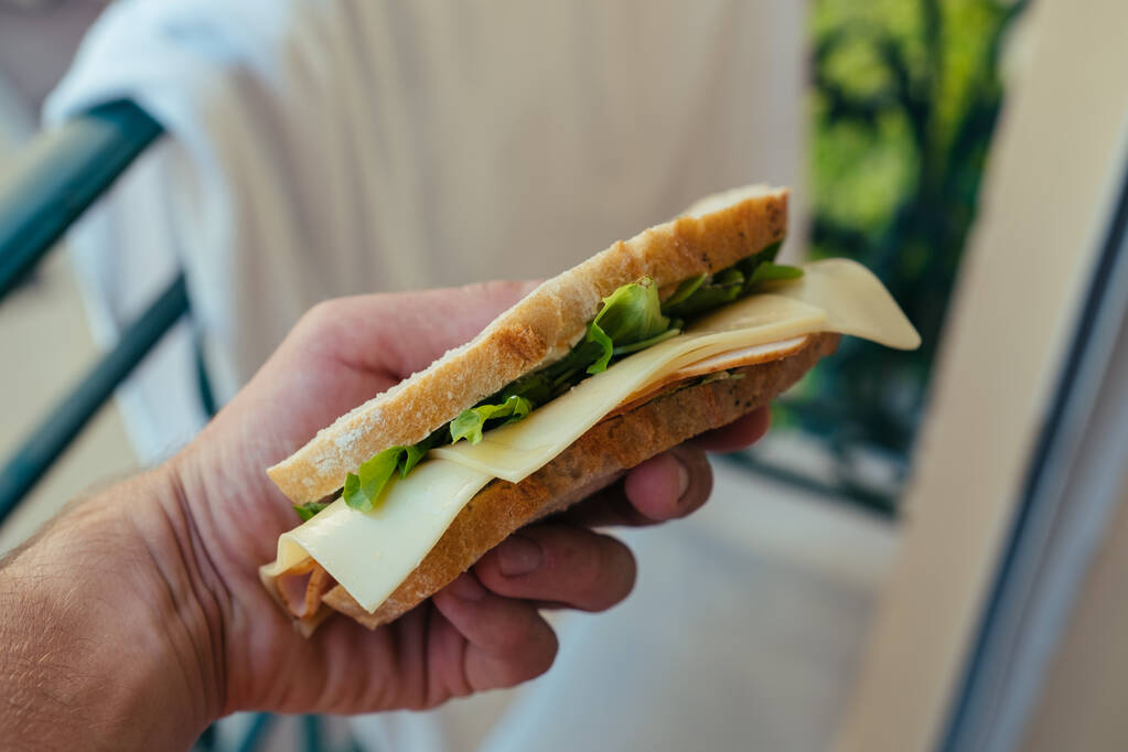 Weißbrot-Sandwich mit Brummen und Salat in der Hand in Monaco - Foto, Bild