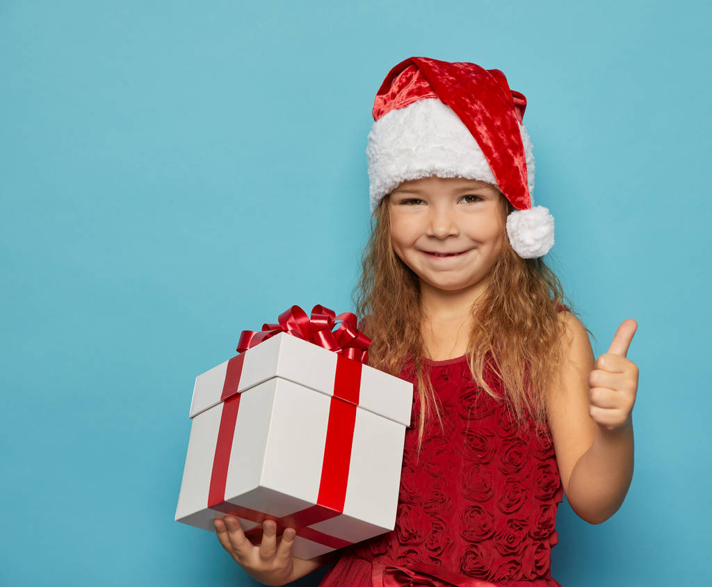  Дівчина в червоному капелюсі Санта тримає різдвяний подарунок
 - Фото, зображення
