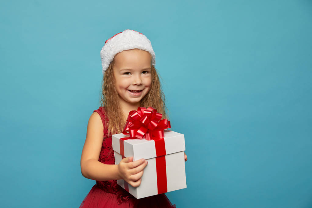  Dívka v Santa červené čepici drží vánoční dárek - Fotografie, Obrázek