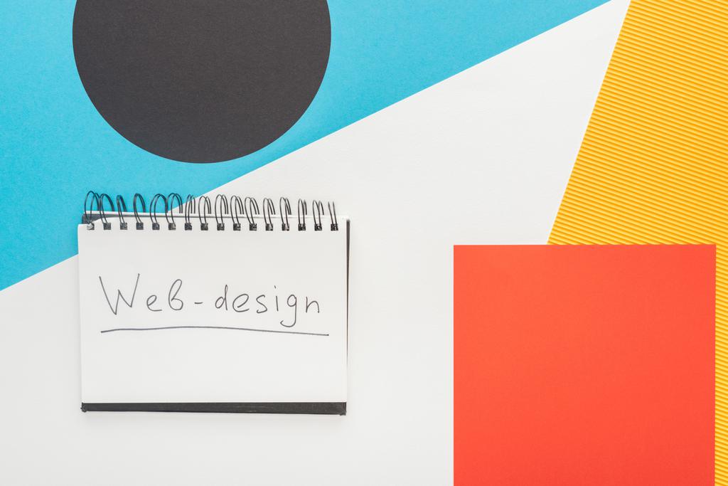 bovenaanzicht van notebook met web-design letters op abstracte geometrische achtergrond - Foto, afbeelding