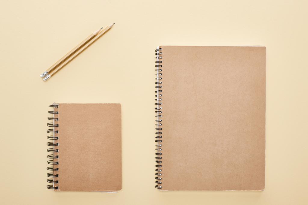 posa piatta con quaderni bianchi di carta con matite su sfondo beige
 - Foto, immagini