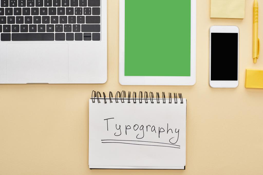 flache Lage mit Gadgets und Typografie-Schriftzug im Notizblock auf gelbem Hintergrund - Foto, Bild