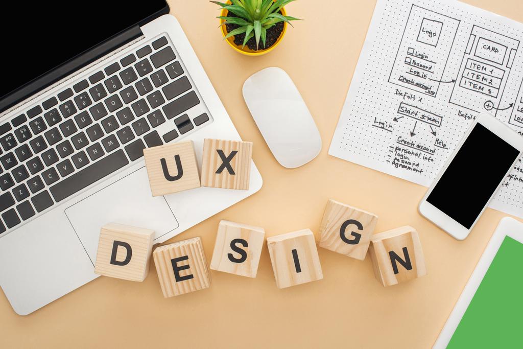 xデザインのレタリング、ウェブサイトのデザインテンプレートとベージュの背景に緑の植物と木製のブロックの近くのガジェットのトップビュー - 写真・画像