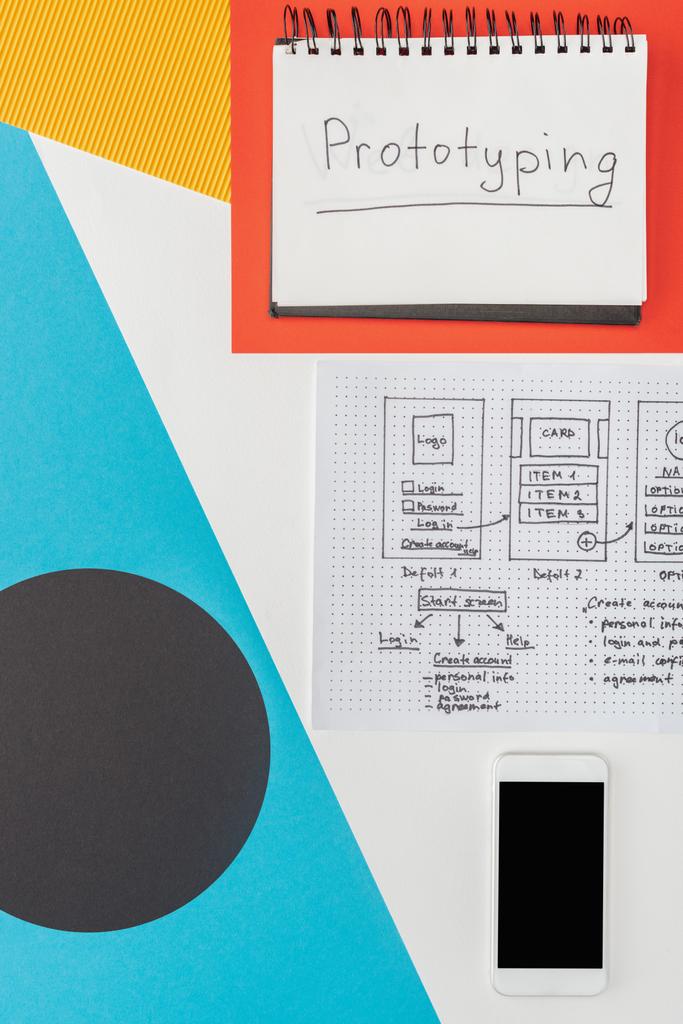 bovenaanzicht van notebook met prototyping letters, smartphone en website design template op abstracte geometrische achtergrond - Foto, afbeelding