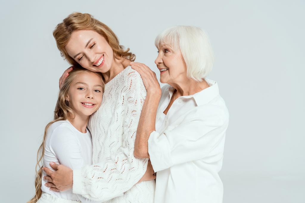 smiling granddaughter, mother and grandmother hugging isolated on grey  - Photo, Image