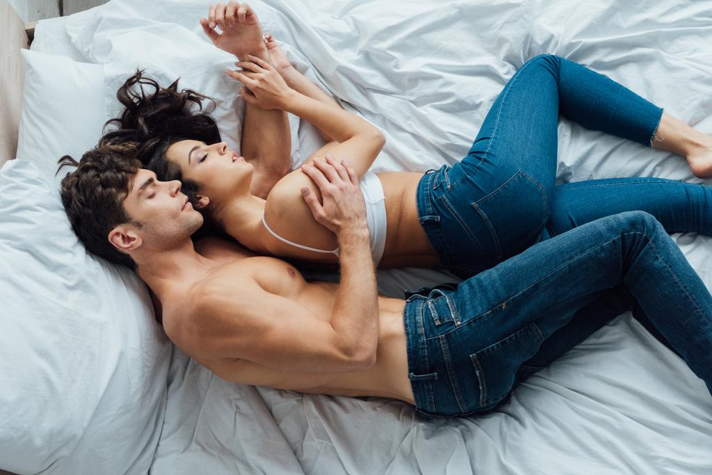 vista superior del hombre sin camisa abrazando novia mientras duermen en la cama juntos
 - Foto, Imagen