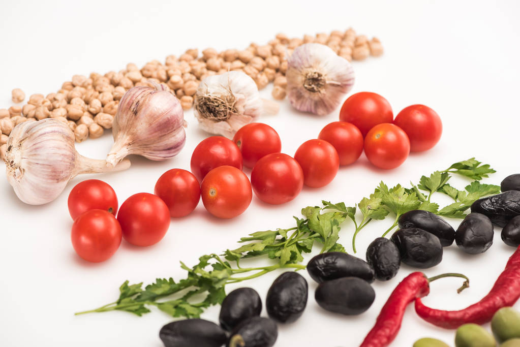 vista de perto de grão de bico, alho, tomate cereja, salsa, pimenta, azeitonas sobre fundo branco
 - Foto, Imagem
