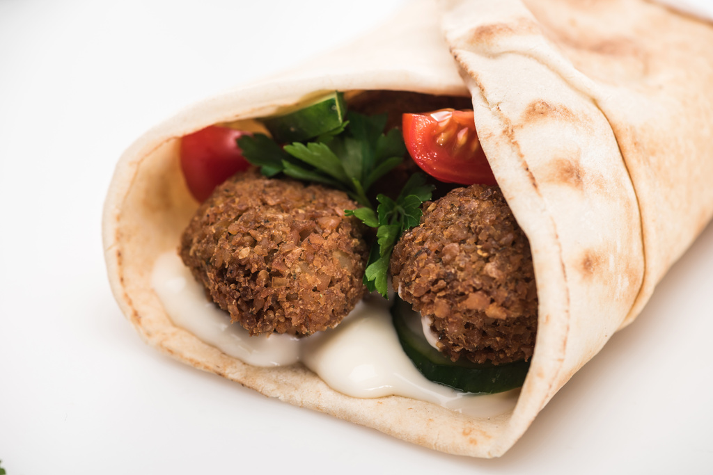close up view of fresh falafel balls in pita with vegetables and sauce on white background - Photo, Image