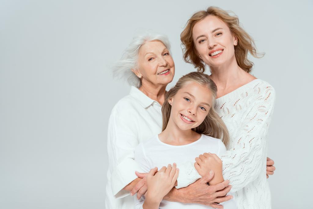 усміхнена онука, мати і бабуся обіймаються ізольовано на сірому
  - Фото, зображення