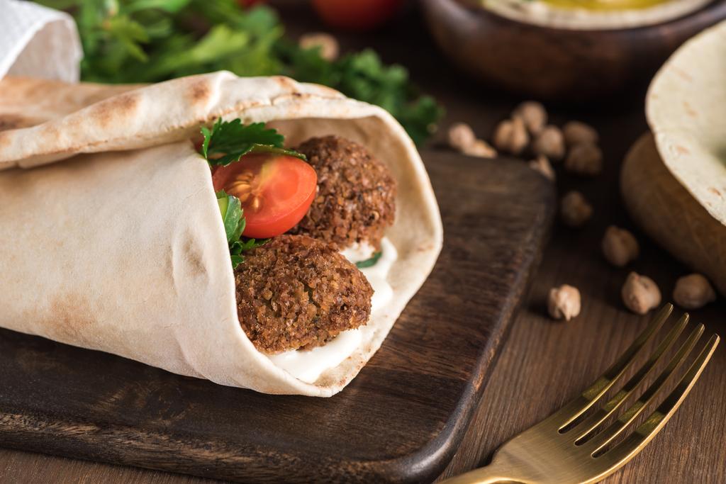 close up view of falafel with vegetables and sauce wrapped in pita on wooden table - Photo, Image