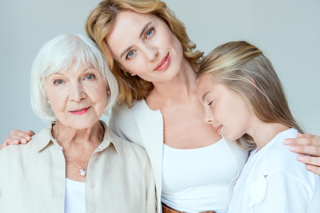 nieta con los ojos cerrados, madre sonriente, abuela abrazo aislado en gris
  - Foto, imagen