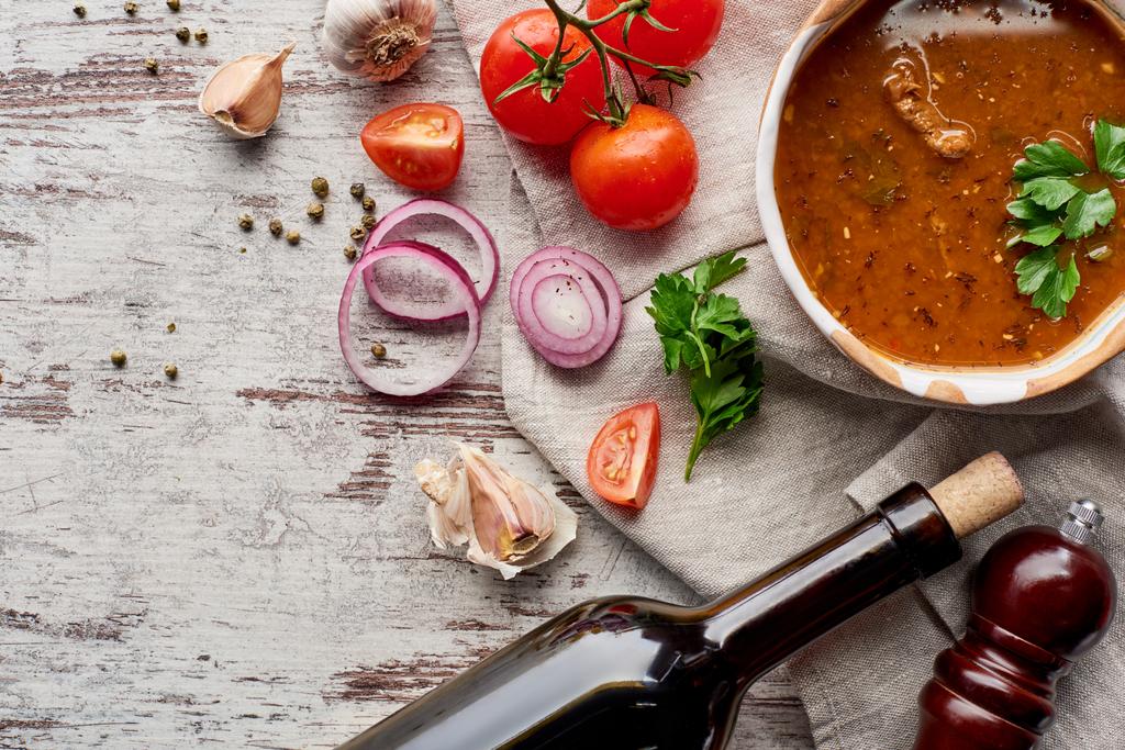 Vista dall'alto di zuppa kharcho, bottiglia di vino, verdure e spezie sul tavolo
 - Foto, immagini