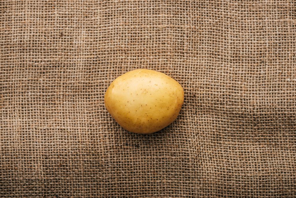 Blick von oben auf Bio-Rohkartoffeln auf braunem rustikalem Sacktuch - Foto, Bild