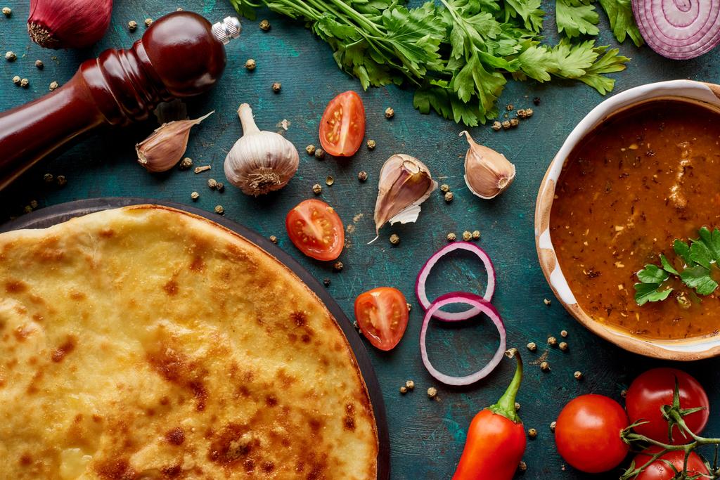Zupa kharcho i imereti khachapuri z przyprawami i warzywami na teksturowanym zielonym tle - Zdjęcie, obraz