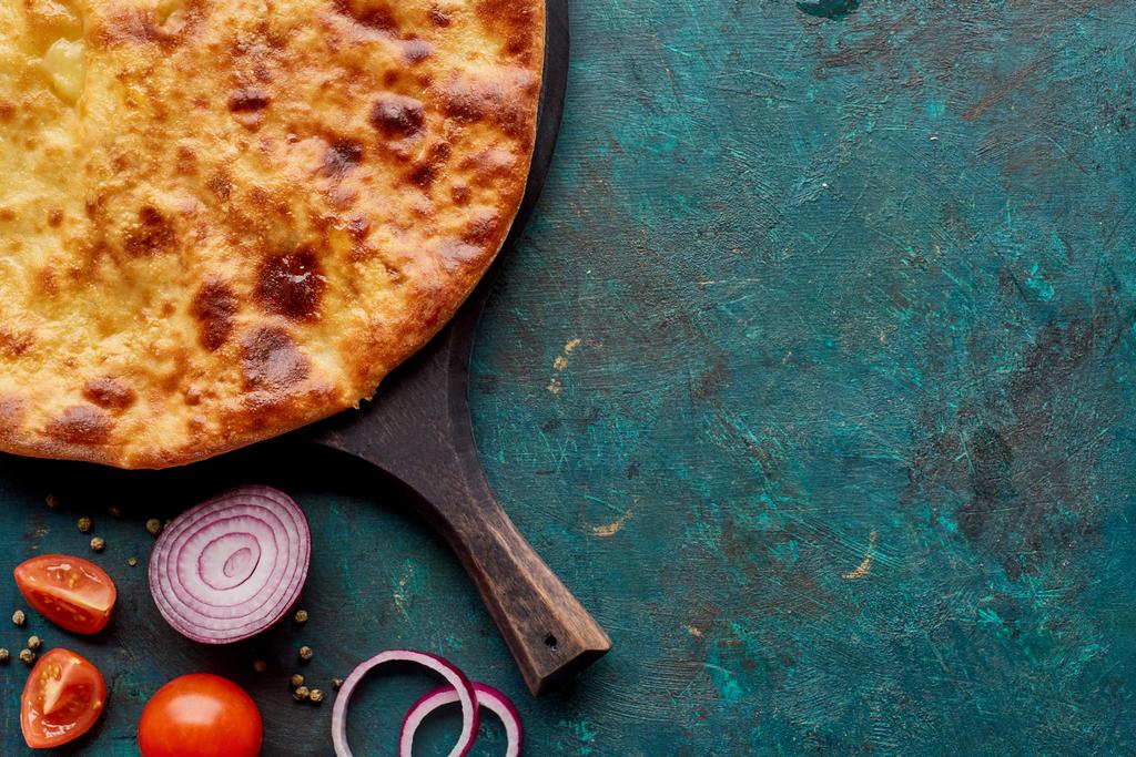Top view of imereti khachapuri with vegetables on textured green background - 写真・画像