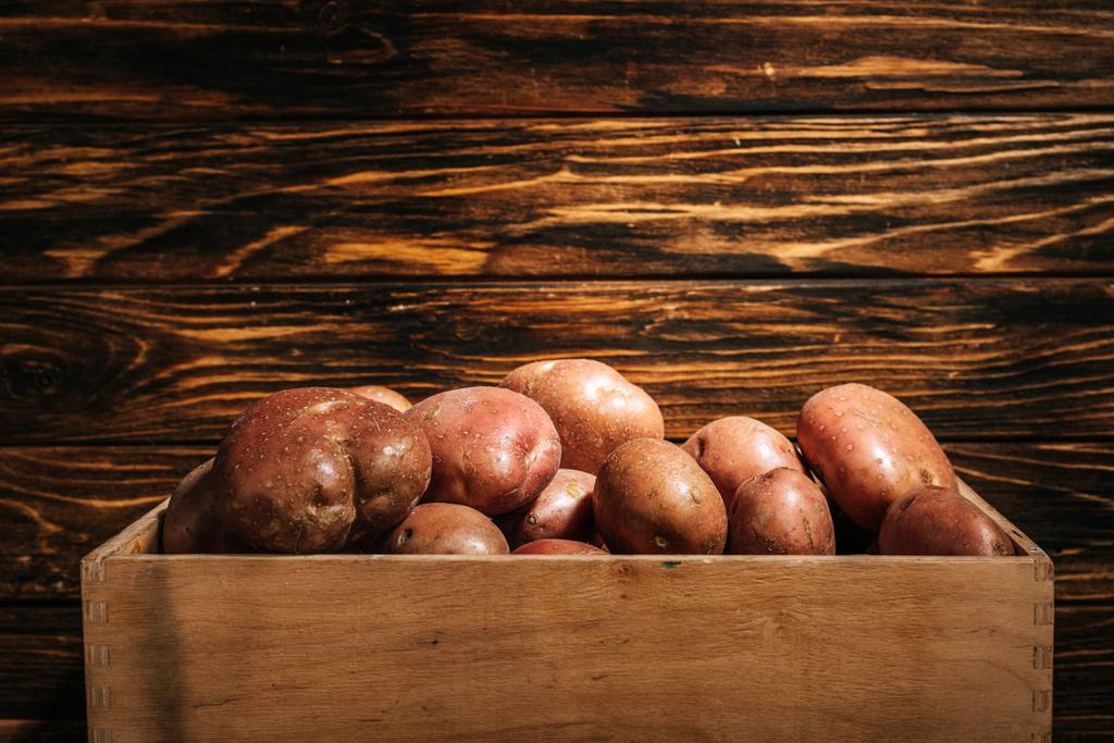 papas frescas maduras en caja sobre fondo de madera
 - Foto, Imagen