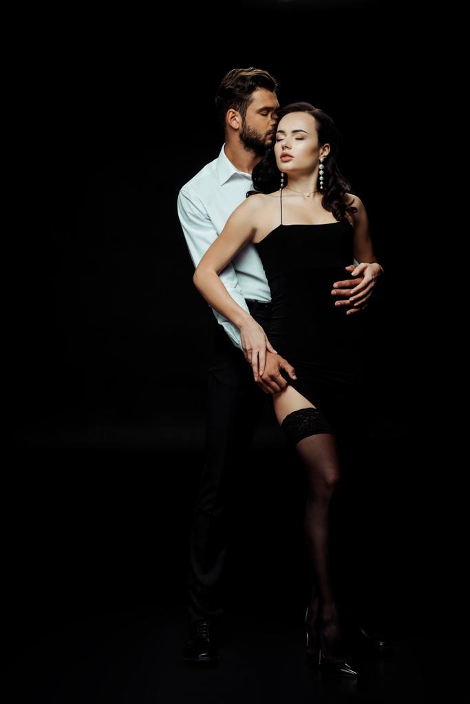 vášnivý muž dotýká sexy žena v šatech izolovaných na černé  - Fotografie, Obrázek