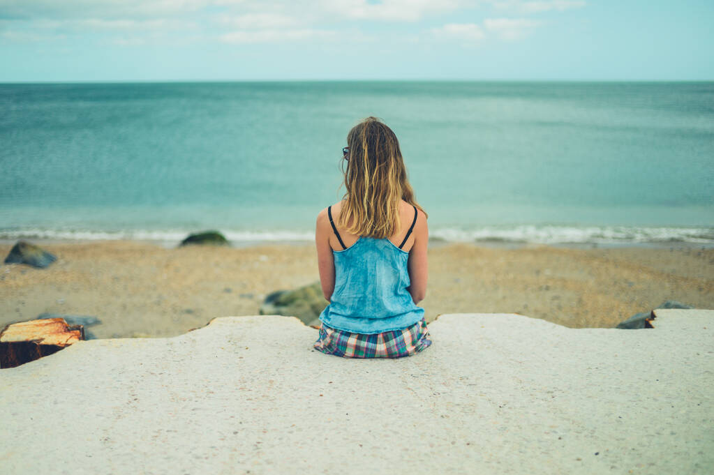 Een jonge vrouw ontspant zich aan zee. - Foto, afbeelding
