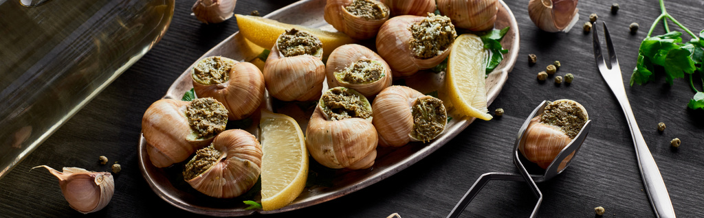délicieux escargots cuits avec des tranches de citron sur table en bois noir avec des épices et du vin blanc, vue panoramique
 - Photo, image