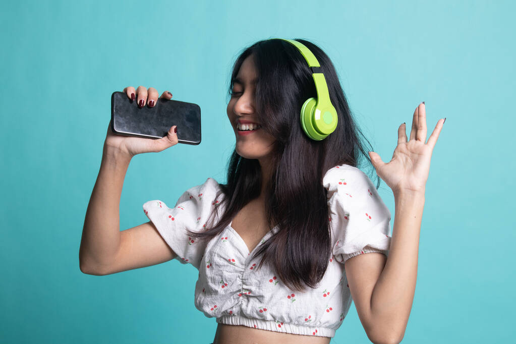Досить азіатська дівчина слухає музику зі своїми навушниками
. - Фото, зображення