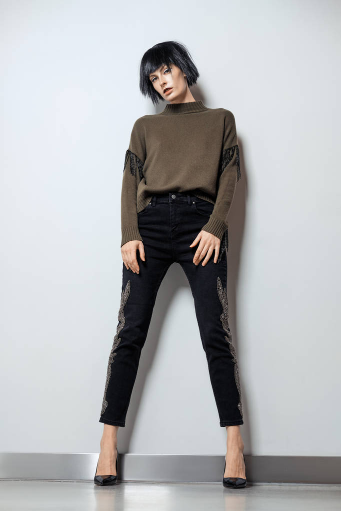 Model in schwarzer Perücke, Pullover mit Fransen und Jeans mit Strass - Foto, Bild