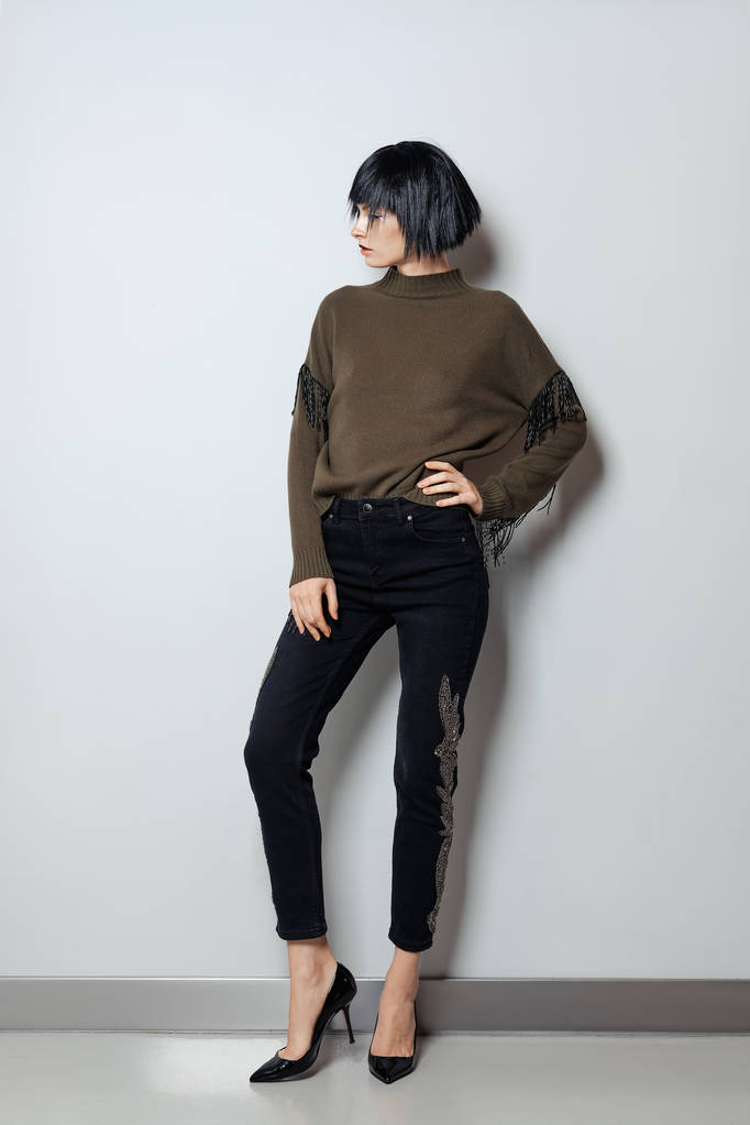 Модель в черном парике, свитер с бахромой и джинсы со стразами
 - Фото, изображение