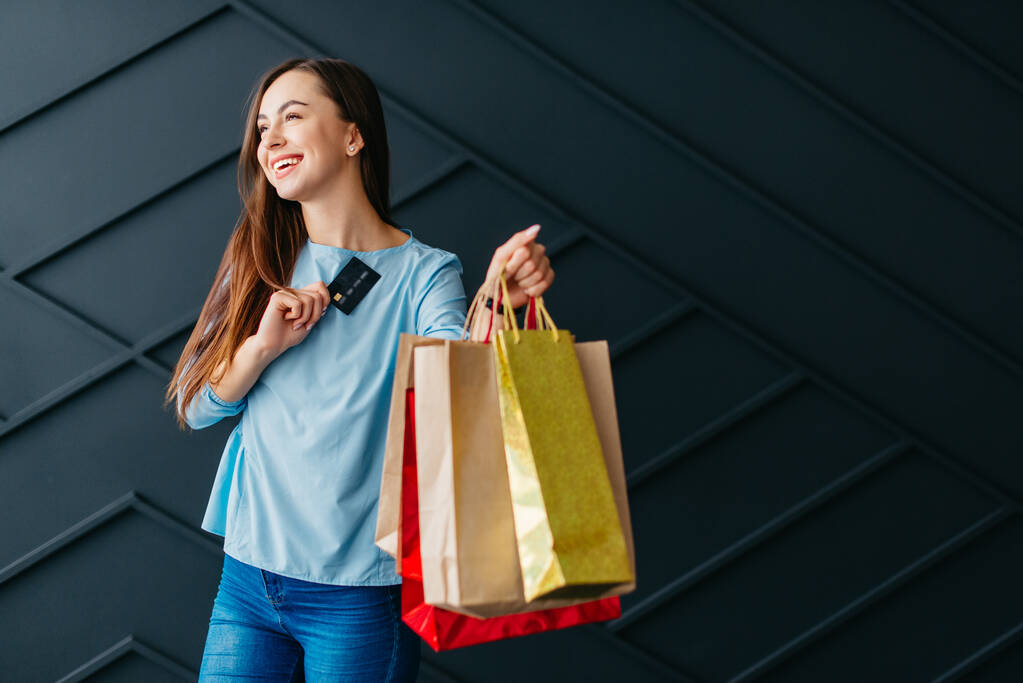 Mujer feliz sosteniendo tarjeta de crédito y bolsas con compras, concepto de viernes negro - Foto, imagen