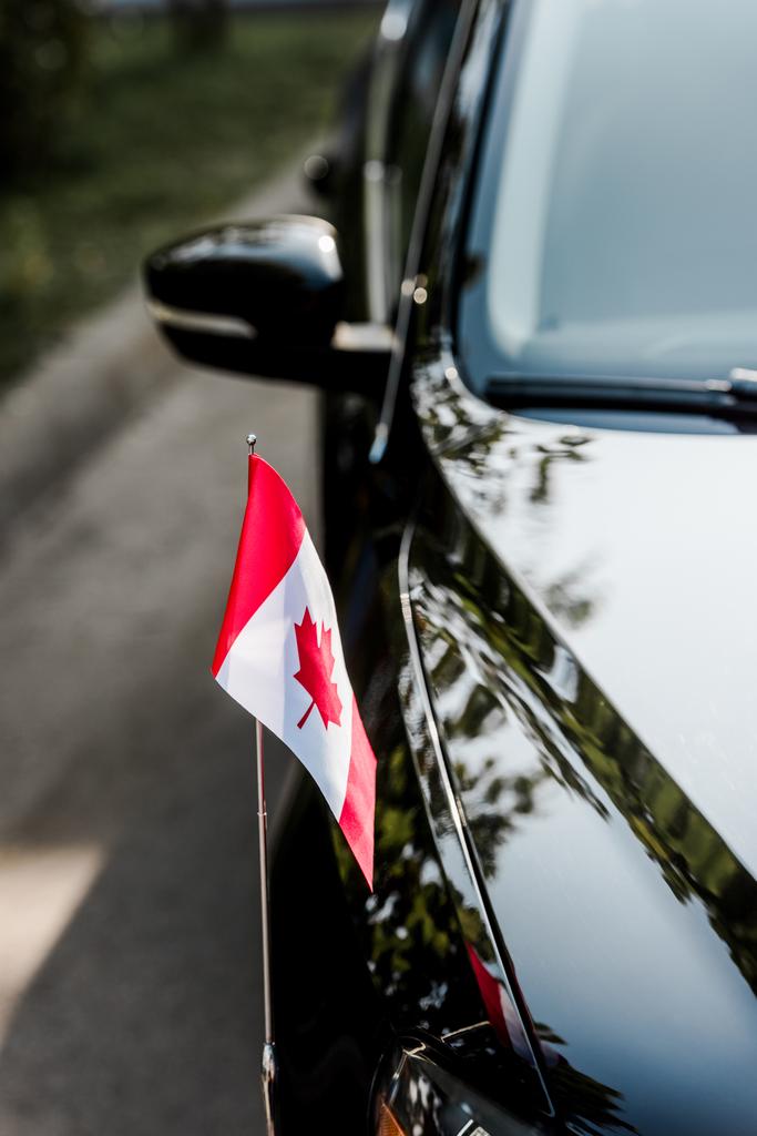 szelektív fókusz kanadai zászló juharfalevél a modern autó  - Fotó, kép